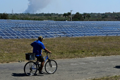 Un homme passe à vélo devant un parc photovoltaïque à Cienfuegos, le 20 mars 2025 à Cuba