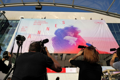 Des employés installent l'affiche officielle du 78e Festival de Cannes sur la façade du Palais des Festivals à Cannes, dans le sud-est de la France, le 11 mai 2025 - Valery HACHE (AFP)