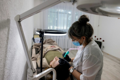 Olena Sologub se fait tatourer les paupières par Ganna Zemliak, à Kramatorsk, en Ukraine, le 6 mai 2025 - Tetiana DZHAFAROVA (AFP)