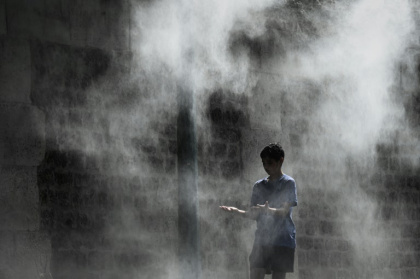 Un jeune garçon profite d'un brumisateur installé sur un quai de la Seine à Paris lors d'une canicule, le 25 juillet 2019 - PHILIPPE LOPEZ (AFP)