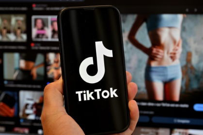 Photo d'illustration du 7 mai 2025 montrant le logo de Tik Tok sur un smartphone devant un écran affichant l'image d'une femme très mince, alors que la tendance "skinnytok" promouvant la minceur inquiète les experts - Loic VENANCE (AFP)