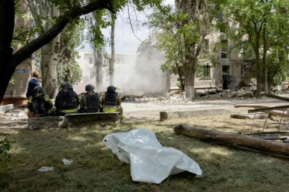 Des secouristes sont assis devant un corps sans vie avec un bâtiment effondré en arrière-plan après une frappe russe à Kramatorsk le 22 juin 2025 - Tetiana DZHAFAROVA (AFP)