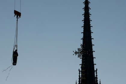 Une grue soulève l'une des 16 statues géantes d'apôtres pour la replacer sur sa base au pied de la flèche de la cathédrale Notre-Dame de Paris, le 23 juin 2025 - GEOFFROY VAN DER HASSELT (AFP)
