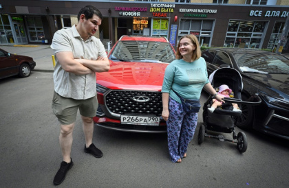 Sergueï Dioujikov, Maria Tiabout et leur bébé devant leur nouvelle voiture chinoise, le 17 juin 2025 à Mytichtchi, une ville de 300.000 habitants au nord-est de Moscou - Alexander NEMENOV (AFP)