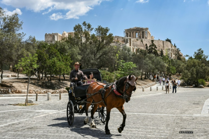 Des touristes en calèche passent devant la colline de l'Acropole, le 29 mai 2025 à Athènes - Aris MESSINIS (AFP)