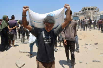 Des personnes se déplacent dans la rue al-Rashid, dans l'ouest de Jabalia, le 22 juillet 2025, après avoir reçu une aide humanitaire dans un centre de distribution situé dans le nord de la bande de Gaza - Omar AL-QATTAA (AFP)