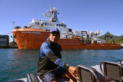 Le biologiste marin Teina Rongo passe en bateau devant le navire de recherche Anuanua Moana, le 12 juin 2025 à Rarotonga, aux îles CooK - William WEST (AFP)