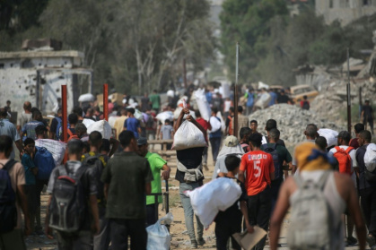 Déplacés palestiniens transportant des sacs d'aide humanitaire après une distribution à Nousseirat, dans le centre de la bande de Gaza, le 26 juillet 2025 - Eyad BABA (AFP)