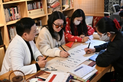 Xu Yan (à gauche) apprend à des étudiants à écrire le nüshu, "écriture des femmes" créée il y a environ 400 ans, lors d'un atelier à Pékin, le 14 avril 2025 - Pedro PARDO (AFP)