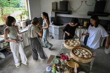 Chen Yani (d), fondatrice du lieu "L'Univers imaginaire de Keke", déjeune avec des participantes dans la cuisine du gîte rural, le 14 juillet 2025 à Hangzhou, dans la province du Zhejiang, dans l'est de la Chine - Jade GAO (AFP)