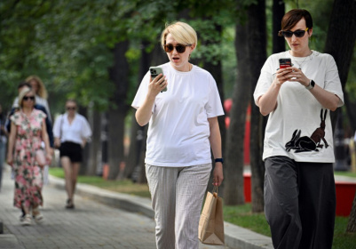 Des femmes utilisent leurs smartphones dans un parc à Moscou, le 30 juillet 2025 - Alexander NEMENOV (AFP)