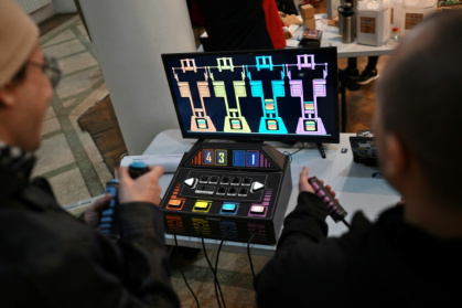 Des personnes jouent à un jeu vidéo fabriqué à partir de composants électroniques recyclés lors de la 3e Rencontre fédérale Cyberciruja à Buenos Aires, le 16 août 2025 en Argentine - Luis ROBAYO (AFP)
