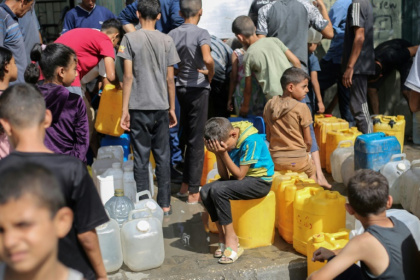 Des enfants palestiniens sont assis sur leurs conteneurs en attendant de les remplir à un point de distribution à Nousseirat, dans la bande de Gaza, le 4 septembre 2025 - Eyad BABA (AFP)