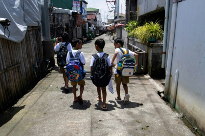 Des enfants sur un trottoir sec, en chemin pour l'école, sur l'île de Pugad, dans la province de Bulacan, le 7 juillet 2025 aux Philippines - Ted ALJIBE (AFP)