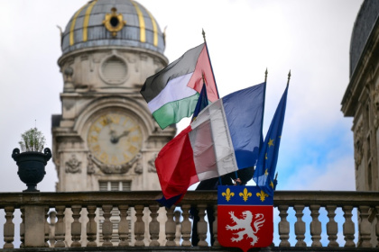 Un employé de la mairie place le drapeau palestinien à côté du drapeau français, du drapeau de Lyon et du drapeau de l'Union européenne, sur l'entrée de l'hôtel de ville de Lyon, le 22 septembre 2025 - OLIVIER CHASSIGNOLE (AFP)