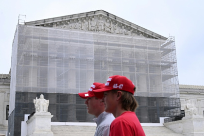 Deux hommes portant des casquettes "Make America Great Again" (MAGA, Rendre sa grandeur à l'Amérique), passent devant la Cour suprême des Etats-Unis, à Washington, le 27 juin 2025 - Alex WROBLEWSKI (AFP)