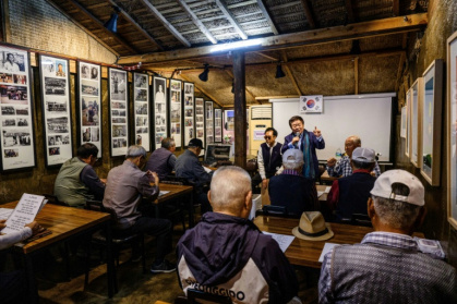 Le bénévole Chang Gwang-hyuck (debout) anime une session de chansons pour les réfugiés nord-coréens et personnes âgées sur l'île de Gyodong, pendant la grande fête familiale d'automne de Chuseok, le 7 octobre 2025 en Corée du Sud - ANTHONY WALLACE (AFP)