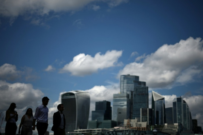 Des passants le long de la rive sud de la Tamise d'où l'on aperçoit le quartier des affaires et financier du centre de Londres, le 14 août 2025 - HENRY NICHOLLS (AFP)