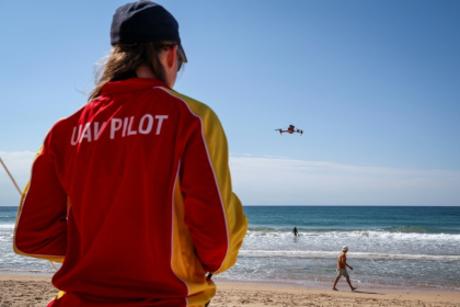 La secouriste Eliza Heys pilote son drone au large d'une plage à Sydney, le 1er octobre 2025 - DAVID GRAY (AFP)