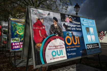 Des affiches électorales en faveur d'une initiative instaurant le devoir civique obligatoire pour tous dans une rue à Genève, le 25 novembre 2025 en Suisse - Fabrice COFFRINI (AFP)