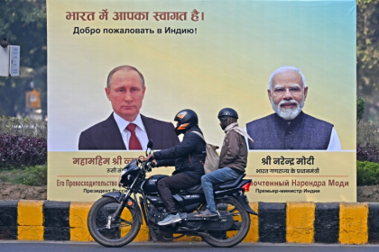 Un motard passe devant des portraits du président russe Vladimir Poutine, à gauche, et du Premier ministre indien Narendra Modi, à droite, à New Delhi le 4 décembre 2025 - Sajjad HUSSAIN (AFP)