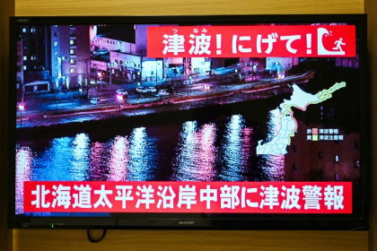 Un avertissement indiquant "Tsunami ! Courez !" (en haut) et "Alerte au tsunami émise pour la côte Pacifique du centre de Hokkaido" s'affiche sur un écran de télévision à Sapporo, au Japon, le 9 décembre 2025 - GREG BAKER (AFP)