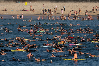 Des surfeurs et des nageurs se sont rassemblés au large de la plage de Bondi, pour rendre hommage aux victimes de l'attentat qui s'y est produit, à Sydney, le 19 décembre 2025 - DAVID GRAY (AFP)