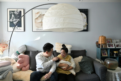 Zhang Xiaofei, 32 ans, et son époux Zhu Yunfei, 36 ans, avec leur fille de trois semaines dans leur appartement de Langfang, en périphérie de Pékin, le 6 mars 2026 - Adek BERRY (AFP)