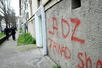 Des policiers patrouillent à proximité d'un mur avec un tag DZ désignant la DZ mafia à Avignon le 13 mars 2025 - GABRIEL BOUYS (AFP)
