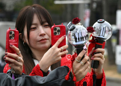 Des fans prennent des photos de bâtons lumineux à l'effigie de BTS à leur arrivée au stade où le groupe de K-pop se produira, à Goyang, le 9 avril 2026 - Jung Yeon-je (AFP)