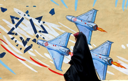 Une femme passe devant une fresque murale anti-américaine et anti-israélienne, à Téhéran, le 8 avril 2026 - Youssef KARWASHAN (AFP)