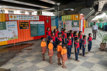 Des élèves chantent l'hymne national indien à "l'école du feu rouge" qui accueille des enfants défavorisés dans des conteneurs aménagés en salles de cours sous un pont autoroutier, le 18 mai 2026 à Bombay - Punit PARANJPE (AFP)