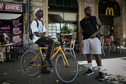 Deux livreurs à vélo se reposent pendant une vague de chaleur estivale près des restaurants en attendant des commandes, à Bordeaux, le 7 juillet 2026 - Philippe LOPEZ (AFP)