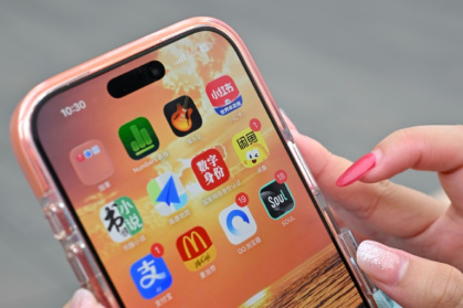 Une utilisatrice de Xiaohongshu se prépare à ouvrir l'application chinoise (en haut à droite) alors qu'elle visite la Cité interdite à Pékin, le 11 juillet 2026 - ADEK BERRY (AFP)