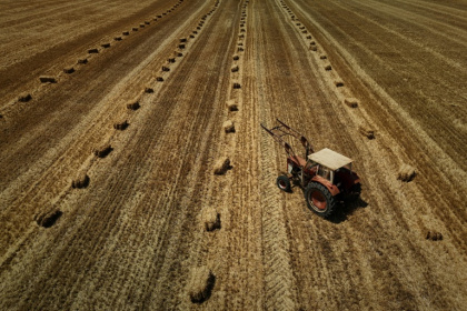 Vue aérienne d'un tracteur dans un champ moissonné, parsemé de bottes de paille, après une récolte de céréales précoce en raison d'une vague de chaleur estivale, près de Ségalas, le 8 juillet 2026 dans le Lot-et-Garonne - Philippe LOPEZ (AFP)